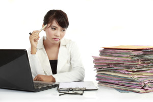 young business woman with laptop and many paper stressed at work